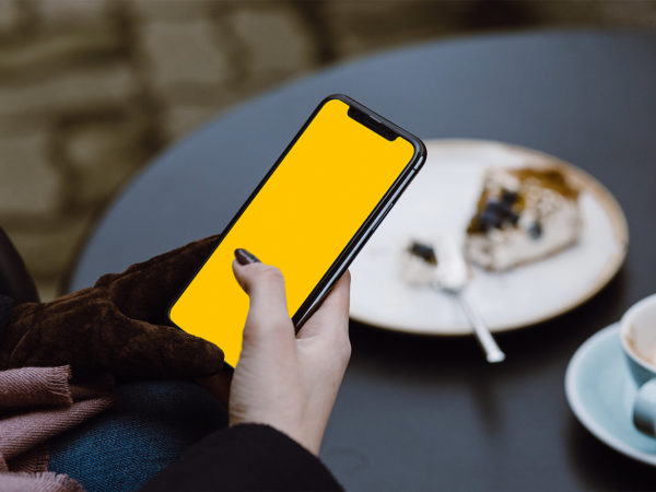 Woman at Cafe with iPhone X in Hand Mockup