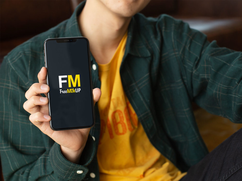 Free Mockup of a Slim Man Holding an iPhone