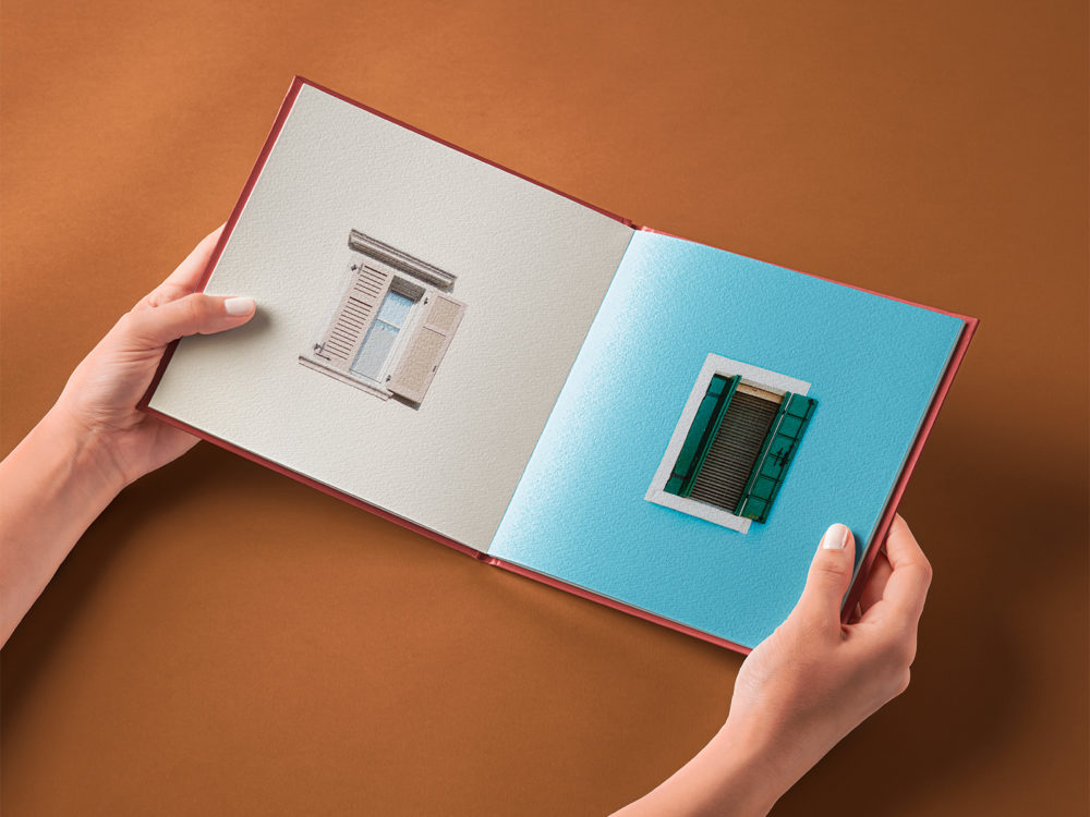 Hand Holding Square Hardcover Open Book Mockup Free PSD