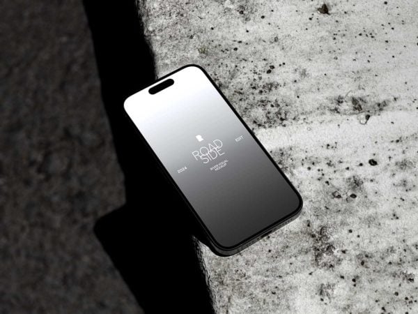 Free iPhone 15 Pro Mockup Lying on Concrete Surface